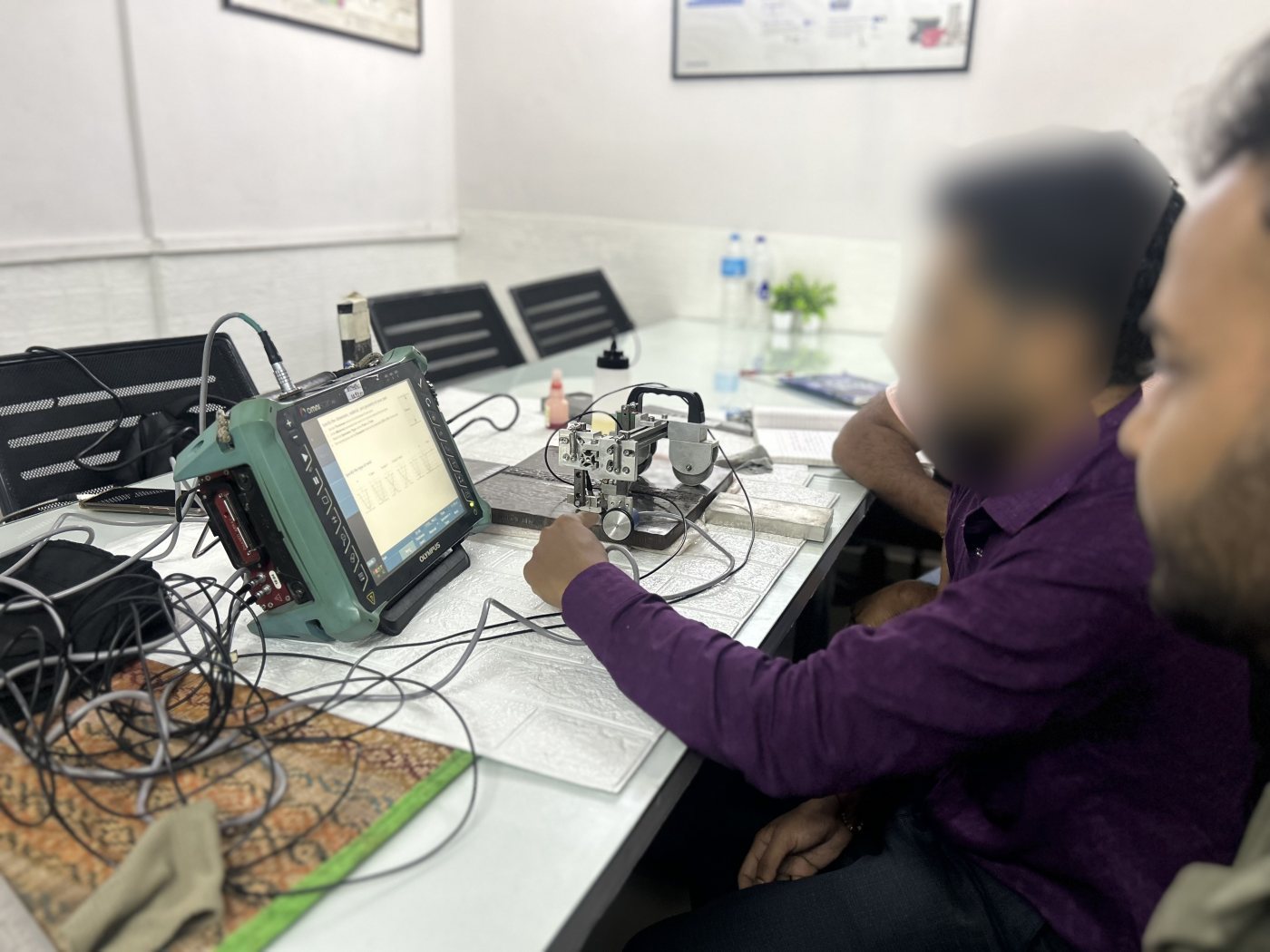 Spark NDT instructors and trainees setting up a transmit receive TOFD station with probe clamp, encoder and OmniScan instrument